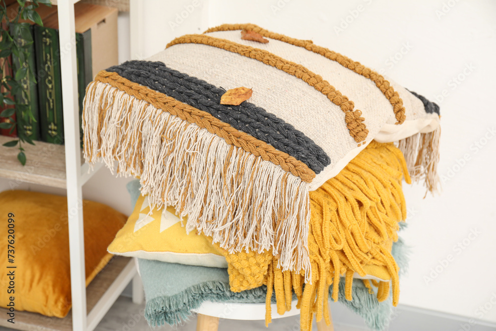 Chair with stack of soft pillows and blankets near shelving unit