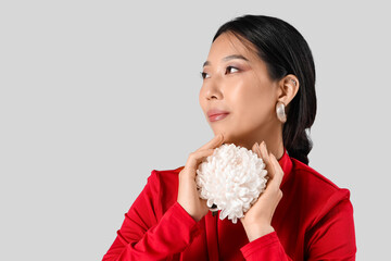 Wall Mural - Young Asian woman with beautiful earrings and flower on white background