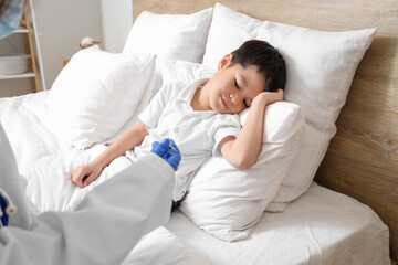 Wall Mural - Ill little Asian boy and doctor with thermometer in bedroom