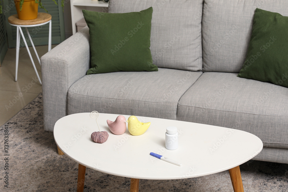 Pregnancy test with pill bottle and decor on table in living room