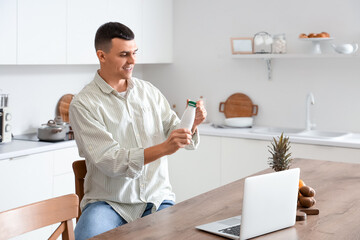 Canvas Print - Young man with bottle of tasty yogurt in kitchen