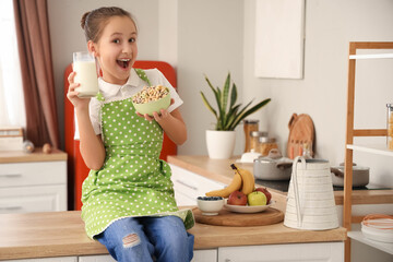 Canvas Print - Happy little girl holding glass of milk and bowl with cereal rings at home