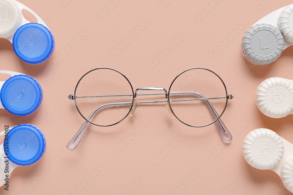 Stylish eyeglasses with containers for contact lenses on beige background