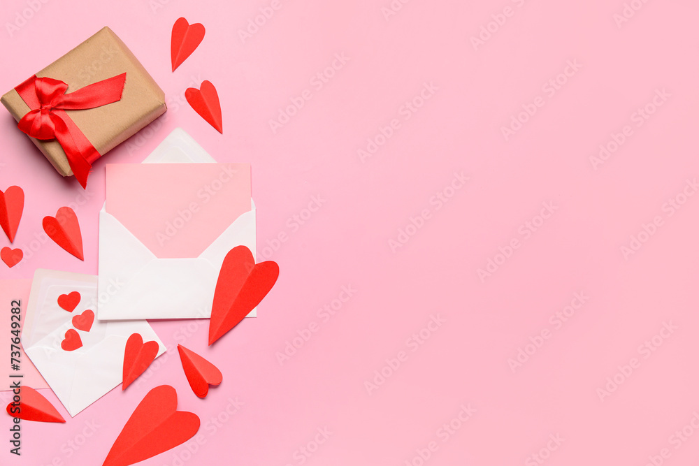 Envelopes with blank card, gift box and red paper hearts on pink background. Valentine's Day celebration