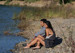 Man And Woman Sitting On Rocky Shore Of River