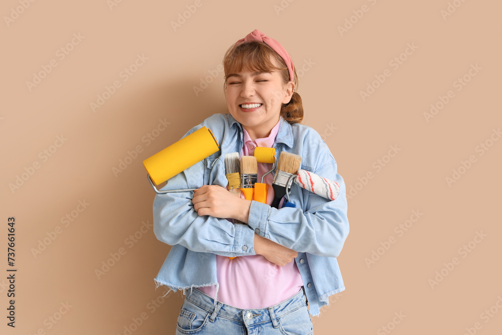 Young woman with paint rollers and brushes on beige background. Repair concept