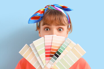 Sticker - Young woman with paint color palettes on blue background. Repair concept