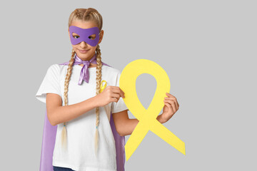 Sticker - Cute teenage girl in superhero costume with yellow ribbon on grey background. International Childhood Cancer Day