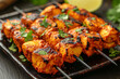 Spicy grilled chicken tikka on skewers with lemon and parsley, suitable for culinary themes and cultural celebrations.