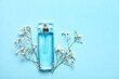 Bottle of perfume with gypsophila flowers on blue background.Top view