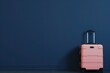 a pink suitcase is leaning against a blue wall