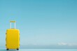 a yellow suitcase is sitting on a blue surface in front of a blue sky