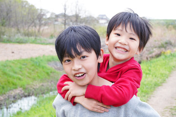 おんぶをして楽しそうに笑っている日本人の仲良しの兄弟