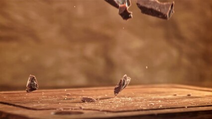 Sticker - Pieces of chocolate fall on a wooden table. Filmed on a high-speed camera at 1000 fps. High quality FullHD footage