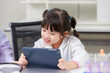 Asian little girl scientist in lab coat reading tablet computer for data learning science at chemical laboratory study room. Education research and development concept learning for kids.