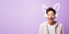 
Photography A Teenage Asian Boy, Aged 17, Posing Playfully With Bunny Ears For An Easter-themed Photo, Against A Muted Pastel Lavender-colored Background With Ample Copy Space