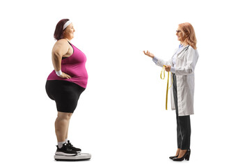 Canvas Print - Doctor talking to a corpulent woman in sportswear on a weight scale