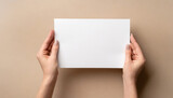 Fototapeta Mapy - Female hands holding an empty white piece of paper with a beige colorful background. Space for text, copy and other graphics. ai generated.