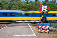 Treinstel Van De Nederlandse Spoorwegen Passeert Een Bewaakte Spoorwegovergang Die Beveiligt Is Met Een Enkele Slagboom En Knipperlicht