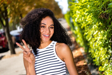 Canvas Print - Photo of cheerful good mood lovely girl walking in summer park laughing an showing v-sign sunny day outside