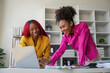 © Natee Meepian - Two businesswoman African American working together using laptop and talking about a business project. team of females executive meeting work in office