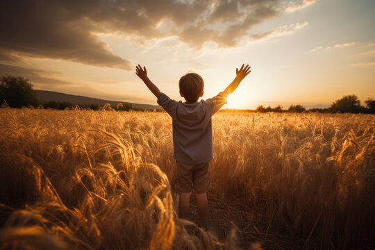 a little boy raises his hands above the sunset sky, enjoying life and nature. happy kid on a summer 