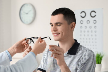 Canvas Print - Vision testing. Ophthalmologist giving glasses to young man indoors