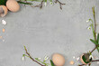 Easter decoration with feathers, branches, flowers, leaves, eggs, egg shells on grey background  with a lot of blank space to fill with content for example Easter holiday wishes. Flat lay.