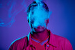 © LIGHTFIELD STUDIOS - portrait of african american man exhaling smoke against blue background with purple lighting, gen z