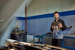 © bnenin - A smiling auto mechanic working at his garage, using a digital tablet.