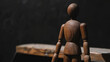Wooden figurine of a man on a dark background.