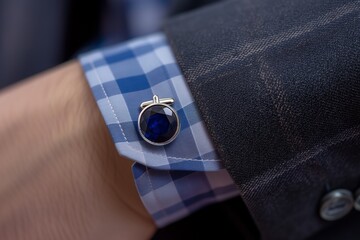 sapphire cufflink on a mans shirt cuff, with a suit sleeve partially visible