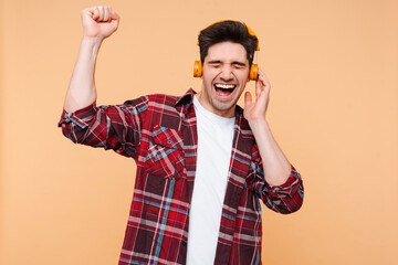 Portrait of handsome smiling man wearing headphones listening music, dancing, having fun