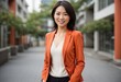 © orelphoto - Happy young asian businesswoman in orange blazer