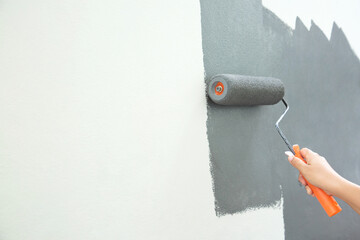 Sticker - Roller Brush Painting, Worker painting on surface wall  Painting apartment, renovating with grey color  paint. Leave empty copy space white to write descriptive text beside.