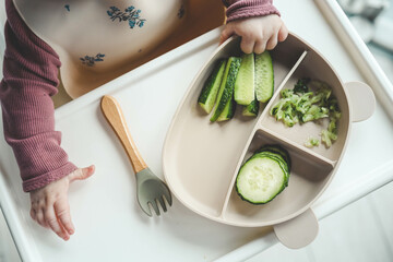 Wall Mural - A child tries a cucumber using the blw, method, first feeding