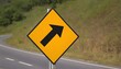 The new symbol reflective yellow right turn sign has a black arrow inside the frame located on the side of the country road