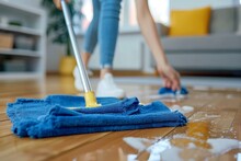 Shallow Focus On The Process Of Cleaning A Shiny Wooden Floor With A Wet Mop And Blue Cloth With Visible Soap Suds