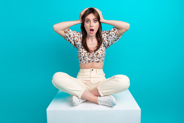 Sticker - Photo of funky shocked lady dressed flower print top sitting platform arms head isolated turquoise color background