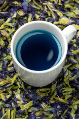 Canvas Print - Cup with blue Butterfly pea flower tea and dried butterfly pea tea flowers around it close up