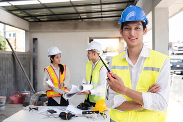 Wall Mural - Portrait of a male engineer at a construction site using a walkie-talkie. Standing in charge of planning a construction project in formal attire, wearing a hard hat, a successful civil engineer.