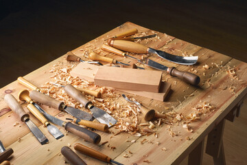 Canvas Print - Hands of craftsman carve with gouge in hands on workbench in carpentry close-up. Wood Carving process