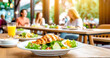 Salat mit Hähnchenstreifen, im Hintergrund ein Restaurant mit Gästen 