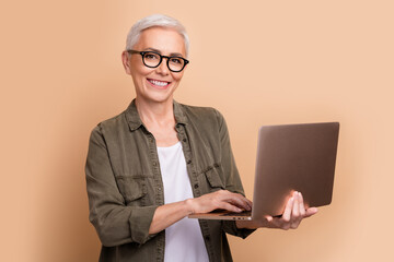 Canvas Print - Photo of it specialist mature age woman strong middle level python developer using laptop linux isolated on beige color background