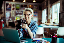 Happy Young Female Photographer Holding A Dslr Camera In Office