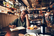 © Davor - Senior waitress doing expenses at a restaurant table