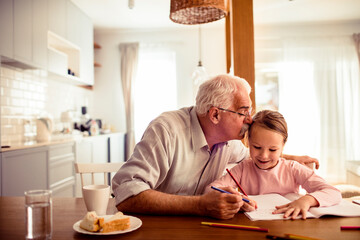 Grandfather and granddaughter drawing at home