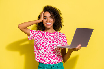 Poster - Photo of cheerful lovely person arm touch head toothy smile hold netbook isolated on yellow color background