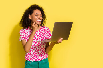 Poster - Photo of cheerful creative lady finger touch chin use laptop empty space ad isolated on yellow color background