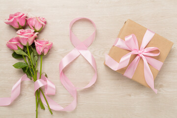 Wall Mural - Composition with pink roses, gift box and eight made of ribbon on wooden background, top view. Women's day concept
